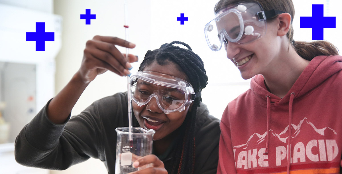 Two students wearing protective gear in a science lab.
