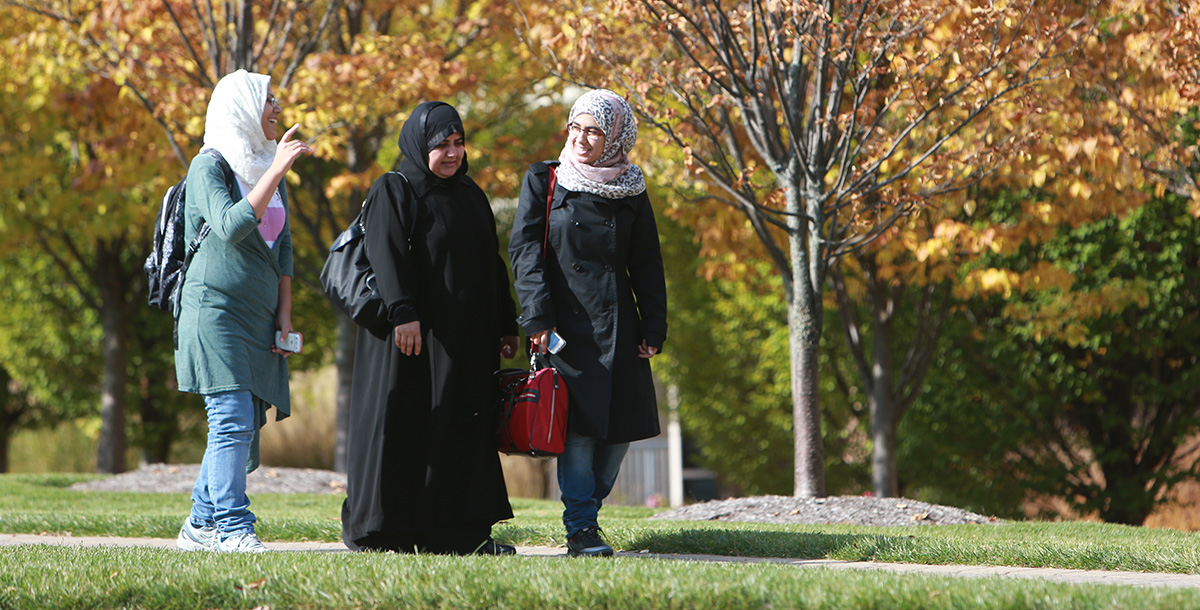Three students walking on campus wearing hijabs