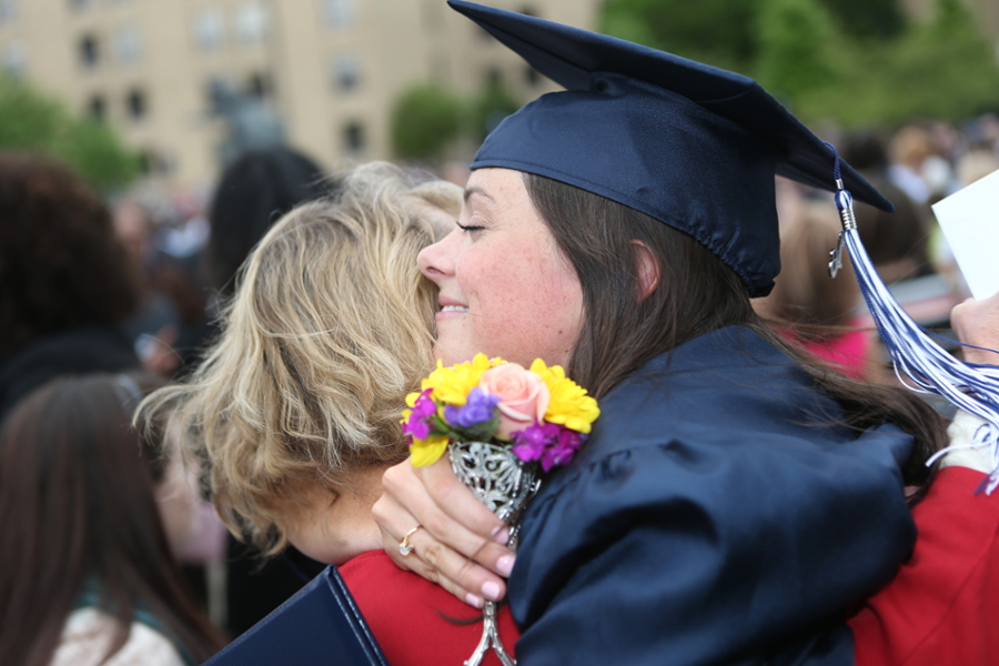 Xavier student in graduation garb hugging a parent