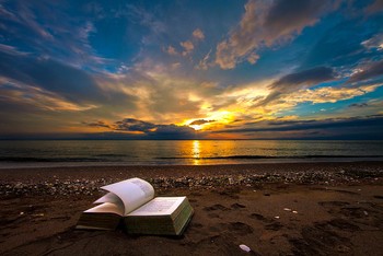 Open book on a beach at sunset