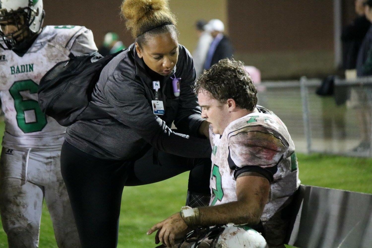 Photo of Nicole Jones helping an injured Football Player