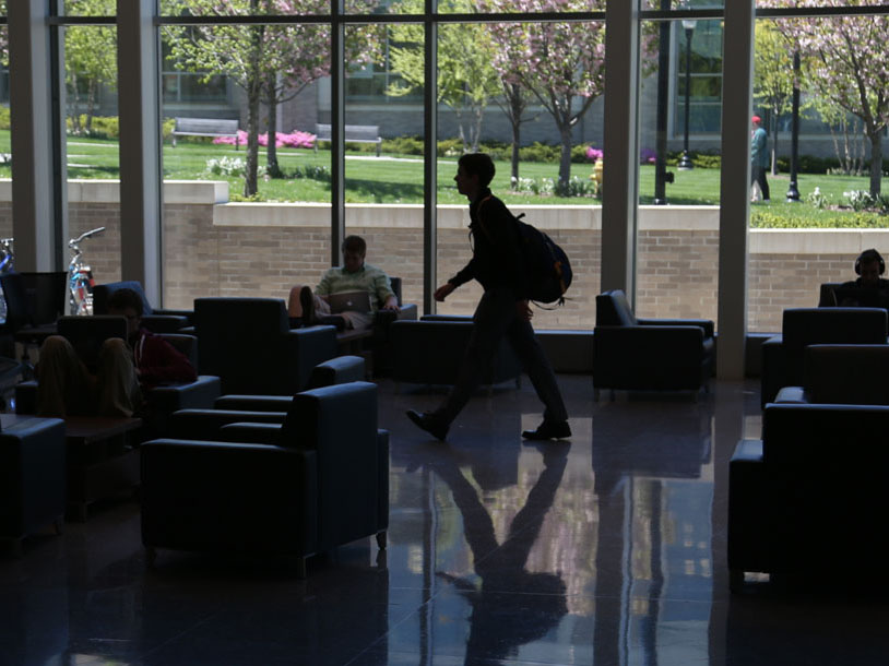 A student wearing a backpack walks across the first floor of Smith Hall.