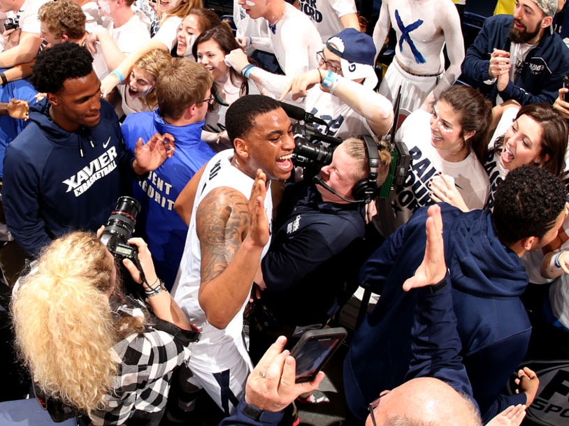The student fan section at Cintas Center embraces a basketball player.