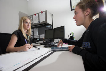 A student speaking with someone behind a desk