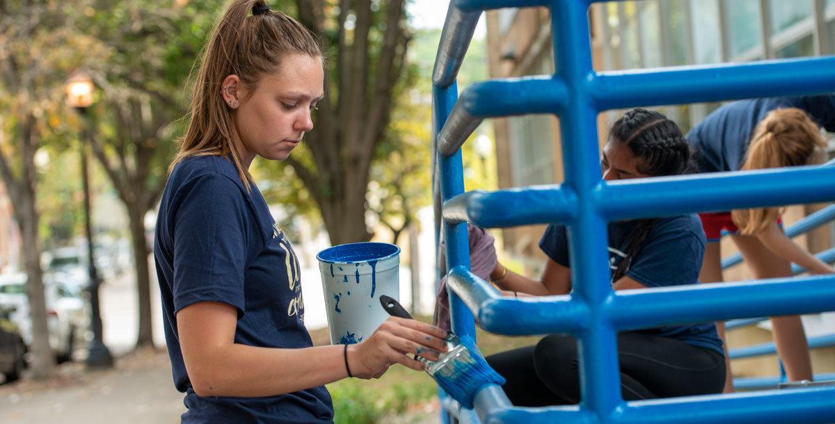 Student painting a railing
