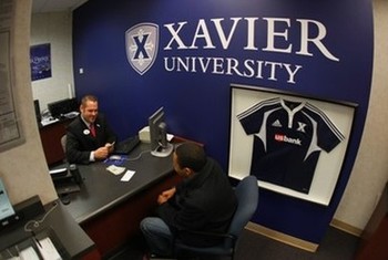 U.S Bank office on the Xavier University campus. A person is talking to a bank teller while sitting on a chair in front of a desk.