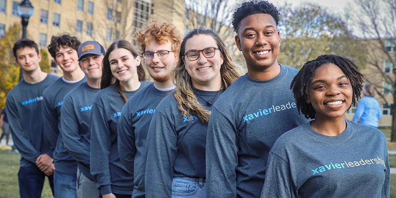 Eight Xavier students standing in a row smiling