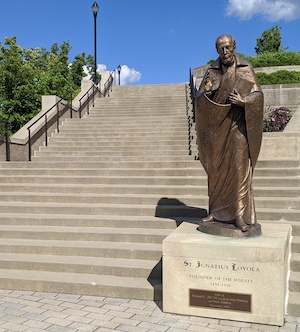 A phoA bronze statue of St. Ignatius in front of concrete steps on Xavier's campus.