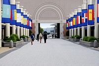 Exterior photo of Business men and women walking in Open Hall with National flags on both sides