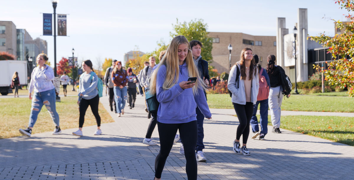 Student walking while looking at cell phone