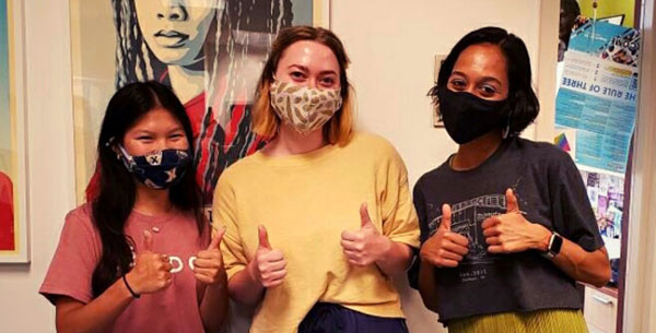 Three masked students giving a thumbs up while tabling