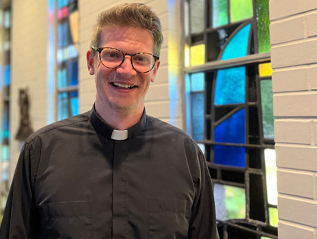 Young man in glasses standing in a chapel in a clerical collar