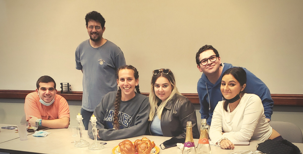 Six students gathered with challah and candles for Shabbat in Gallagher