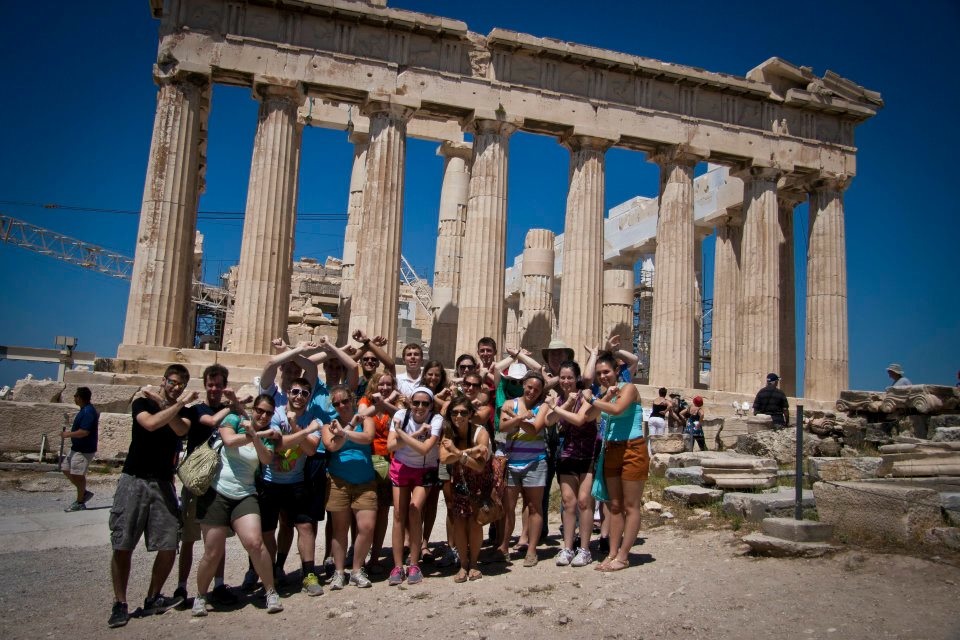 Students holding up an X shape in front of the Parthenon
