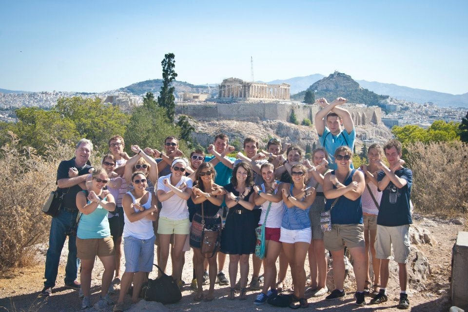 Students holding up an X shape with their arms while on a Study Abroad trip in Greece
