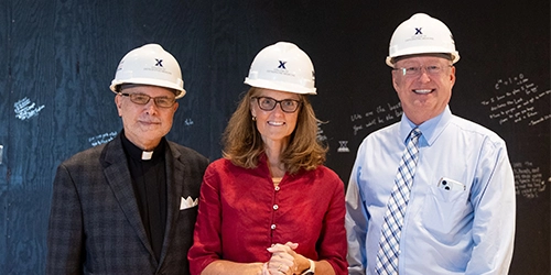 Three people wearing hardhats inside the chapel