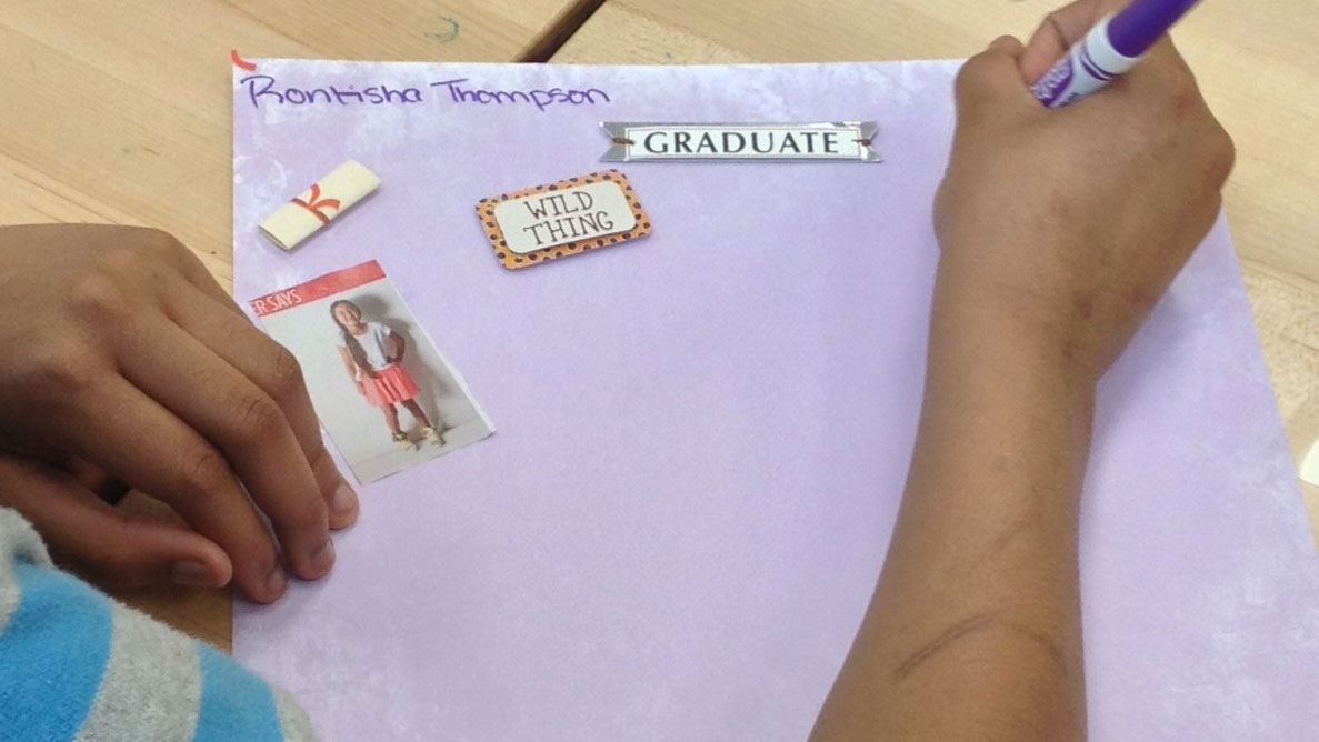 Student writing on page with stickers
