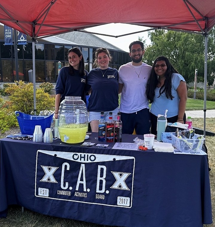 Commuter Activities Board Members wearing 'CAB' T-shirts and standing in front of lemonade booth