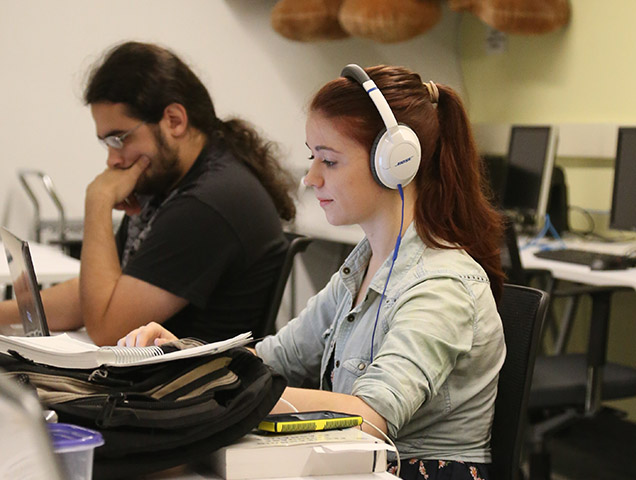 Computer science majors working on desktop computers with headphones on
