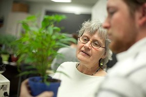 Professor and student examining a plant in a pot