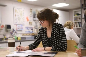 Student writing in a notebook in a classroom