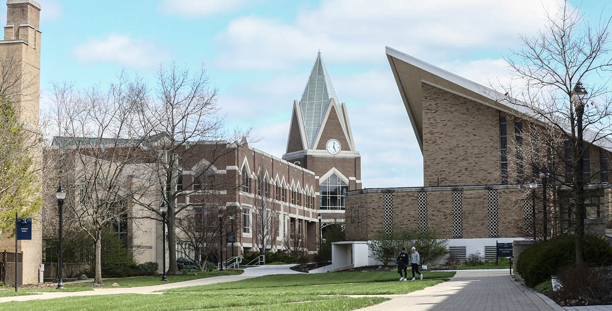 The exterior of Gallagher Student Center on a sunny spring day. Two students walk along the sidewalk in front of the building.