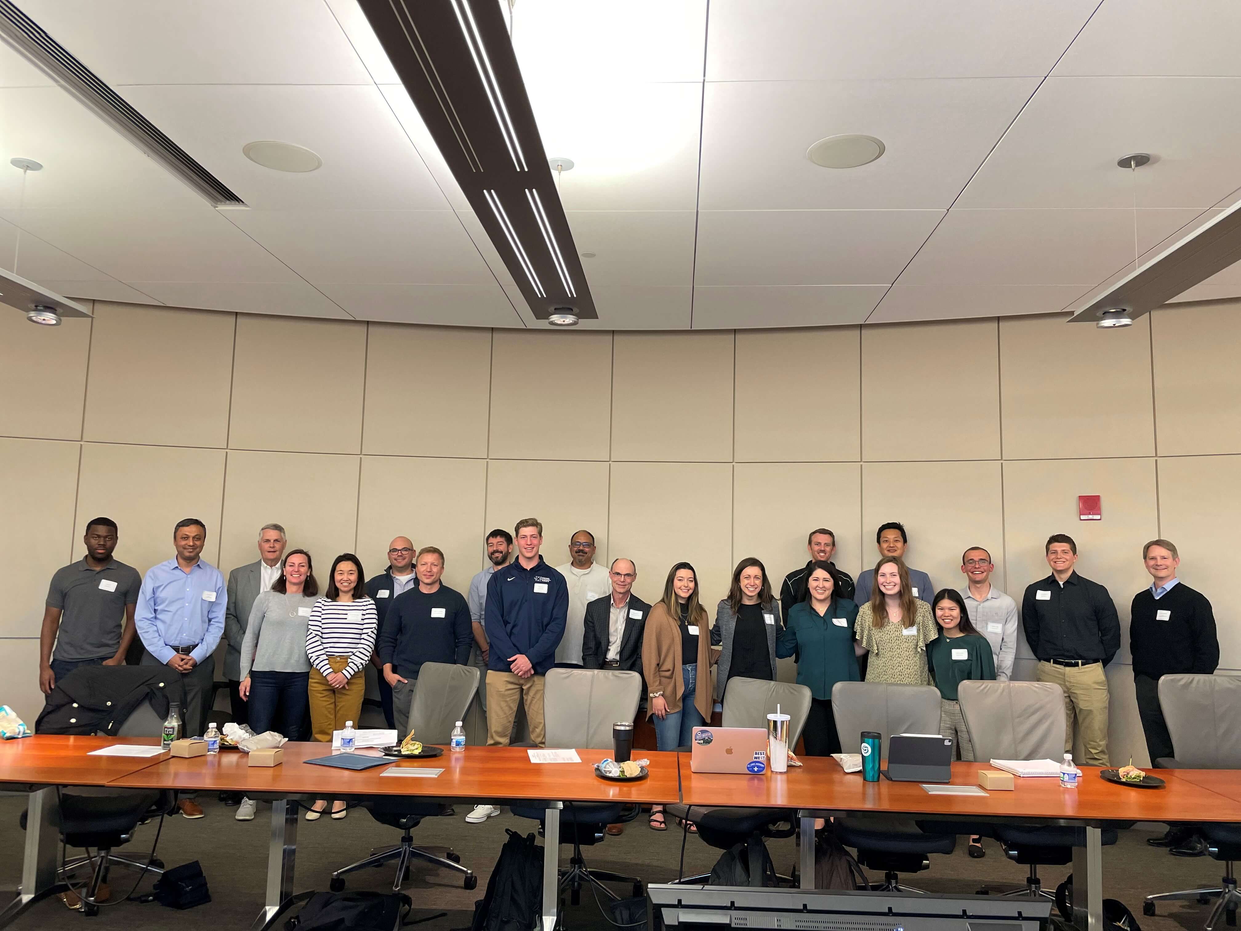 Photo of 21 individuals standing behind a conference room table