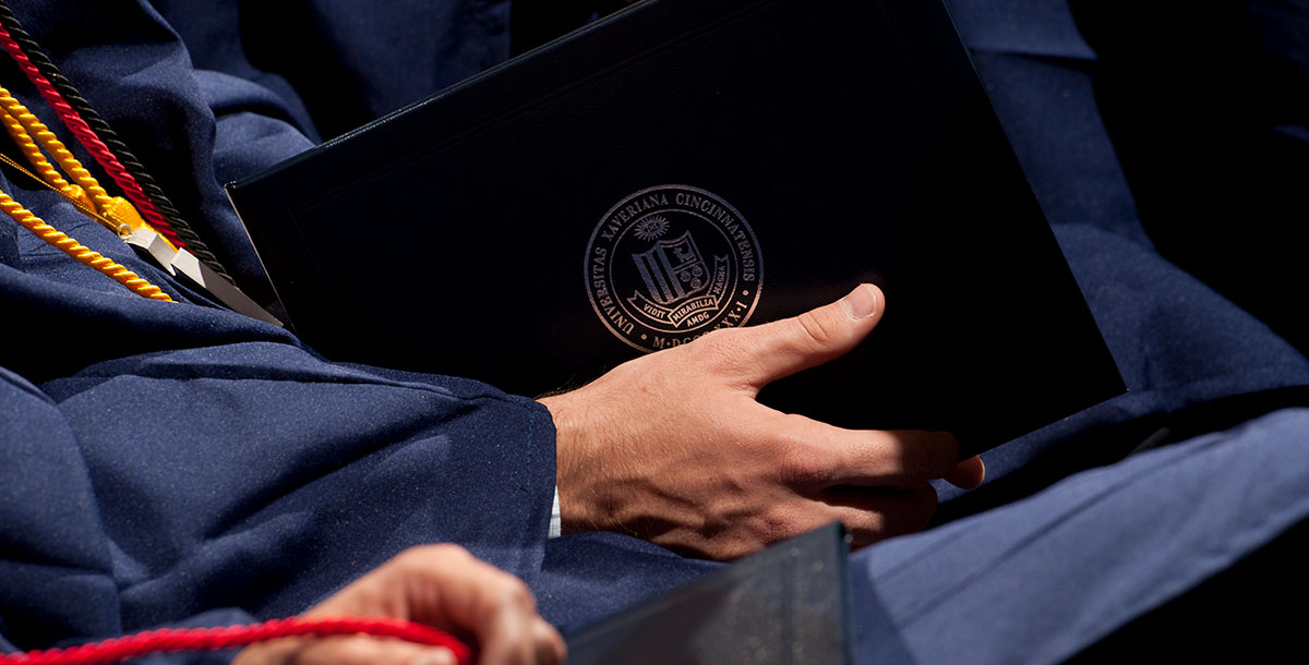 Student holding the physical copy of their degree incased in a leather booklet