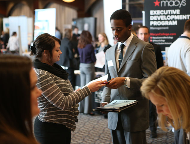 Entrepreneurship and Innovation major connecting with a professional at a career fair 