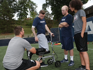Exercise science majors helping an athlete on the soccer field with an assistive walking device