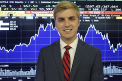 Photo of Clayton Stumler in front of a stock graph