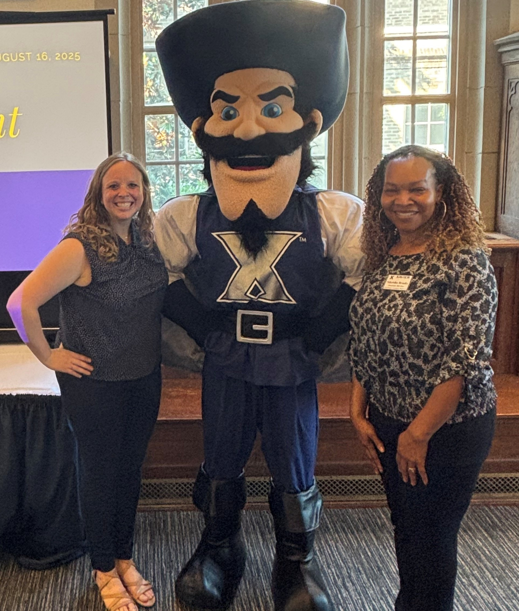 Image of Nikeisha Brooks and Jamie Kuhlmeier standing with Xavier University's mascot D'Artagnon