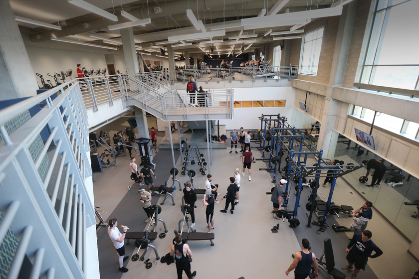 A view of the weight room in the health United Building. About twenty people are using the weight machines in this photo.