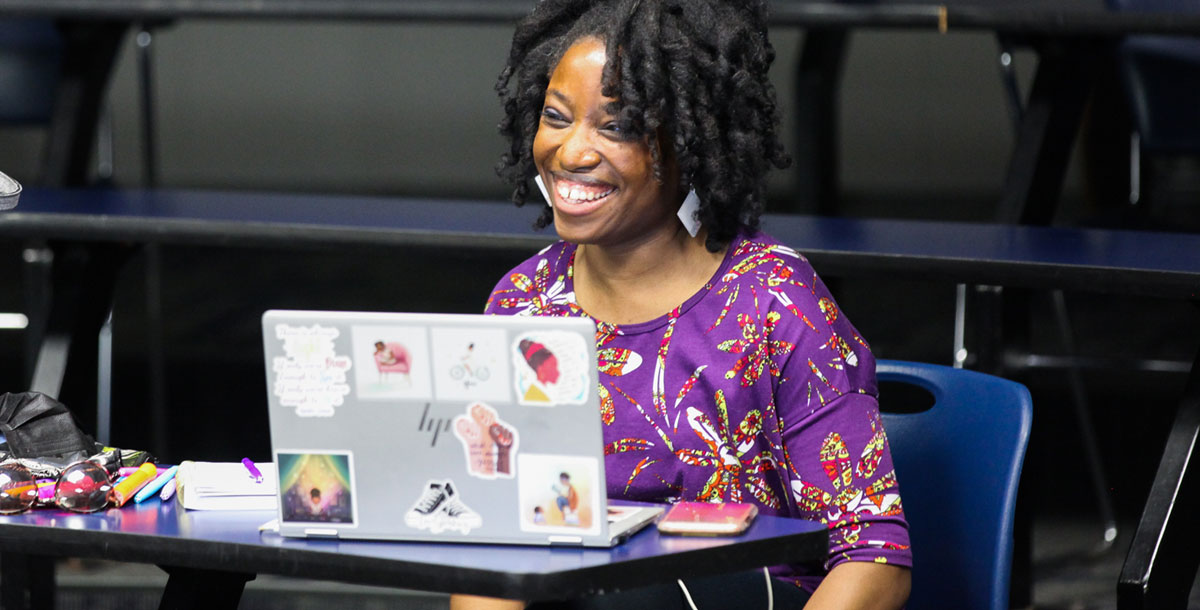 A Xavier student sits at a desk while looking at the screen on a laptop