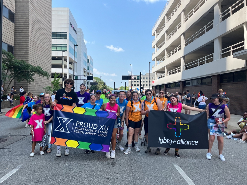group picture of Xavier Students holding Proud XU and LGBTQ+ Alliance flags