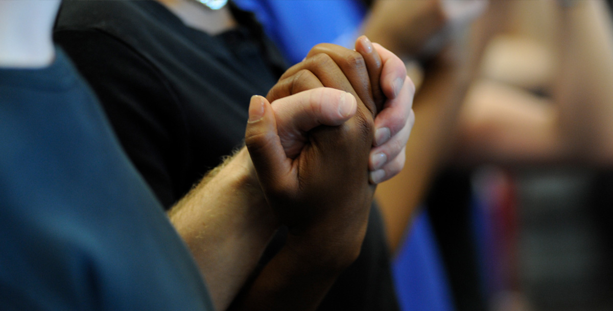 A closeup of two people holding hands during prayer in church