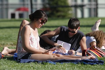 Two students sitting on a blanket on the grass 