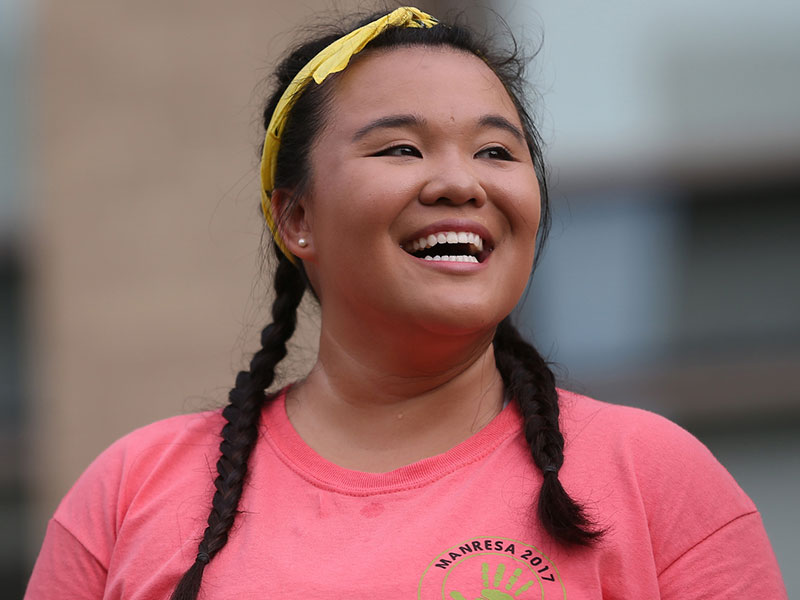 A Xavier student wearing a pink shirt smiles.