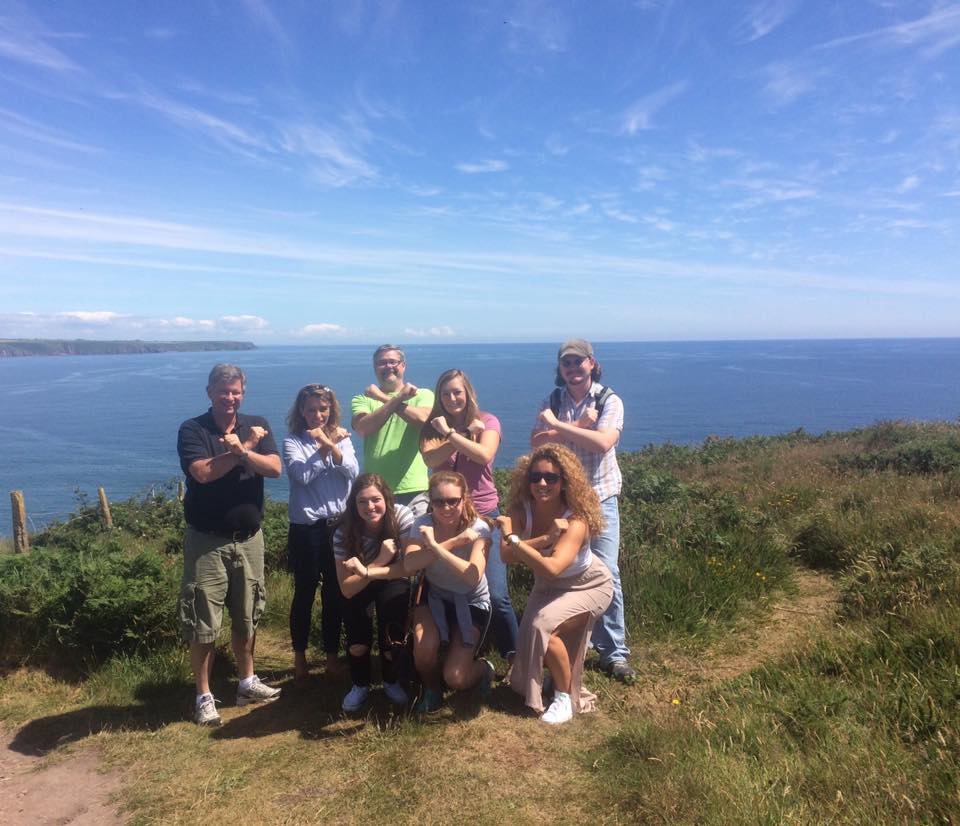 Xavier students crossing their arms into an x while visiting the Cliffs of Moehr in Ireland