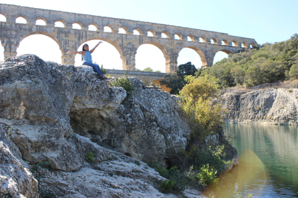 Photo of Student sitting on a small cliff in front of an Ancient Roman aqueduct