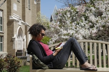 Photo of a Student reading on a bench