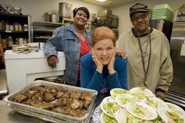 Three people smiling in front of two large plates of food