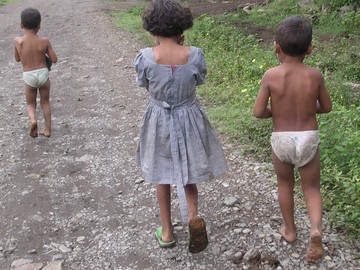 Three children walking along dirt road