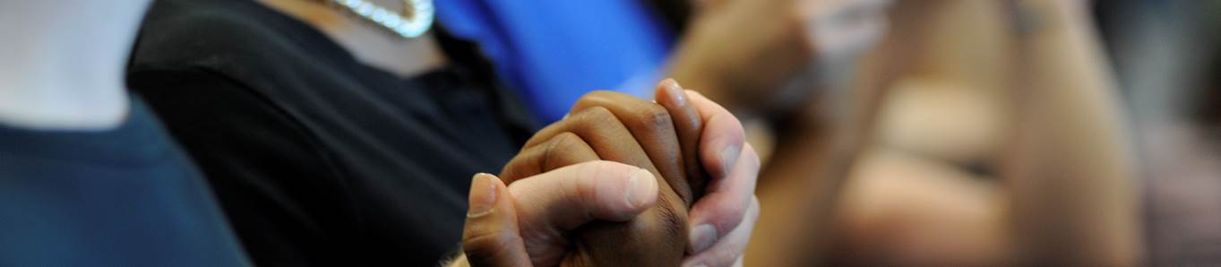 Two people holding hands in prayer