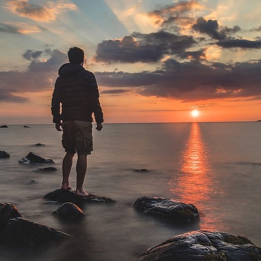 Person standing on beach looking at sunset