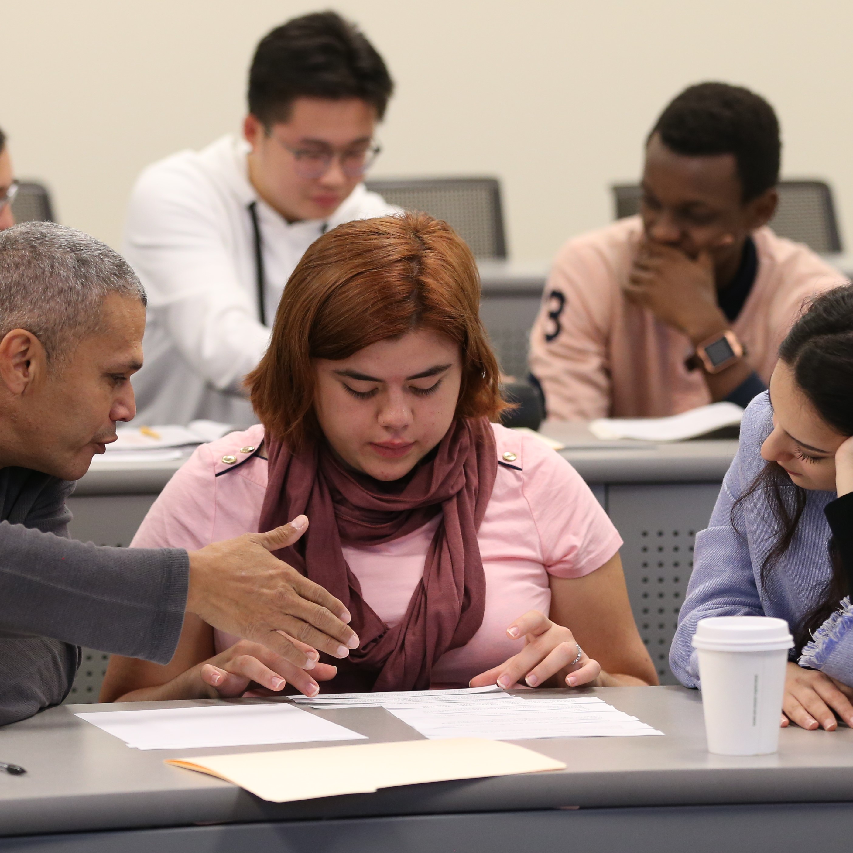 People looking at a piece of paper in a classroom