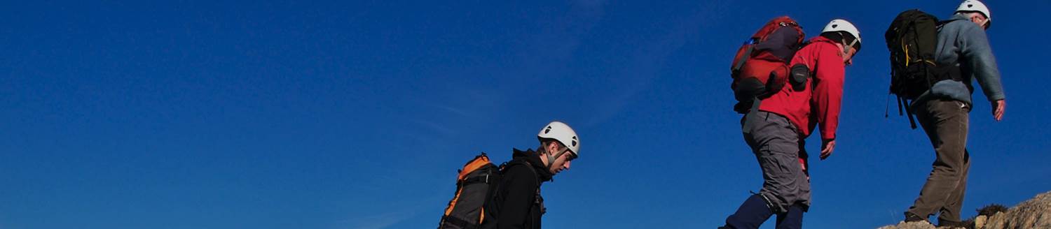 Three people climbing up a hill with hiking gear