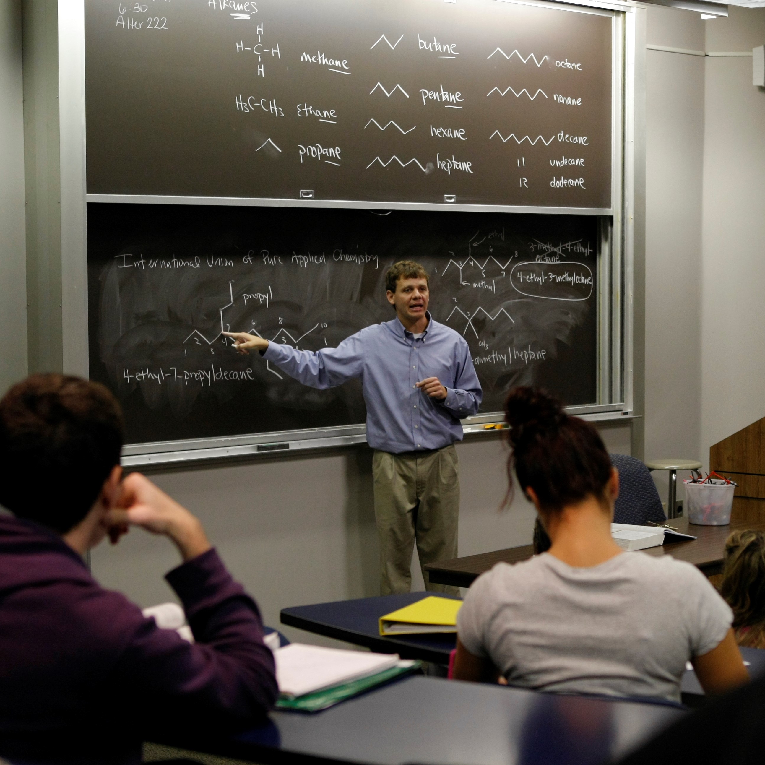 Professor pointing at chalkboard during class