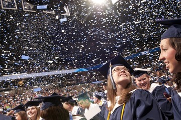 Graduate looking up at confetti in Cintas Center at Xavier University