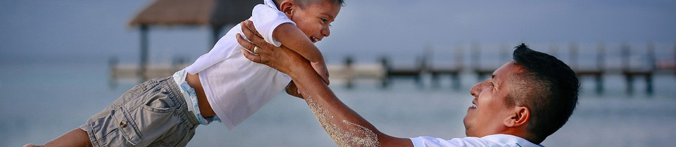 A father lifting his son in the air on a beach